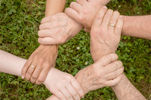 Six hands holding their neighbor's arm to form an interlocking circle, to illustrate empathy and understanding